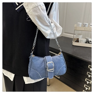 Dettaglio borsa a spalla in denim con catena d'argento e grande fibbia metallica