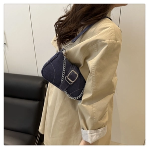 Dettaglio borsa a sella in denim blu con catena d'argento e fibbia decorativa