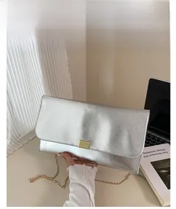 Détail d'une pochette argentée en cuir Saffiano avec chaîne dorée et fermoir métallique