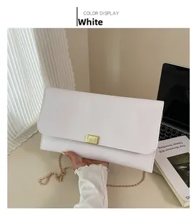 Vue détaillée du sac baguette blanc avec boucle dorée et bandoulière chaîne en décor de bureau