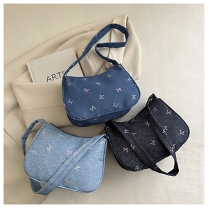 Detailed overhead view of denim shoulder bags with colorful butterfly embroidery patterns