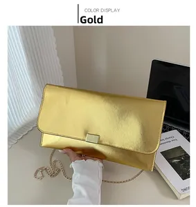 Détail d'une pochette métallique dorée texturée avec un fermoir rectangulaire à pression