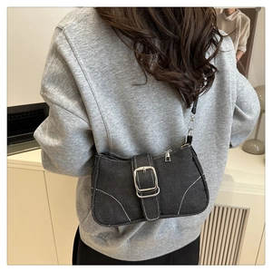 Dettaglio borsa baguette in denim nero con cuciture bianche e fibbia decorativa