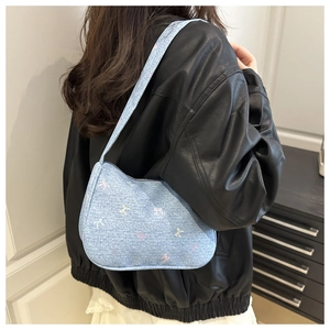 Detail of light blue denim underarm bag with colorful mini bow pattern and texture