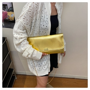 Detail of a shiny gold metallic crossbody bag with a square metal buckle and chain strap