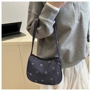 Close-up of small navy denim shoulder bag with pink and white embroidered bow patterns