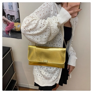 Détail d'un sac enveloppe doré métallisé avec une boucle carrée en métal doré brillant