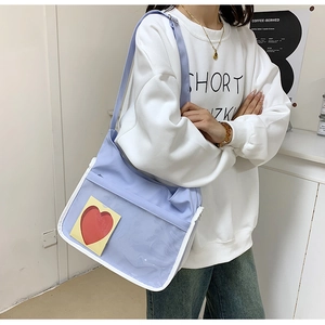 Détail d'un sac bandoulière en nylon lilas avec poche transparente et passepoil blanc