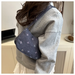 Detail of blue denim shoulder bag with pink and white bow embroidery for women