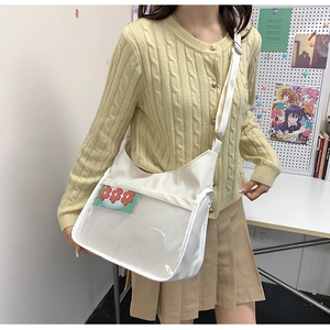 Détail du sac bandoulière en toile blanche avec fenêtre PVC transparente et breloque fleur