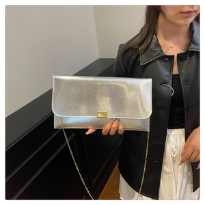 Detail of silver textured envelope clutch with gold buckle and chain strap on model