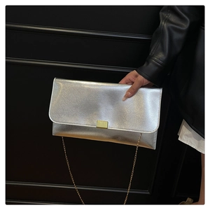 Detail of silver textured envelope clutch with gold hardware and fine chain strap