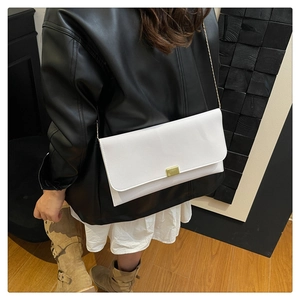 Close-up of a white minimalist leather envelope bag with gold buckle and chain strap