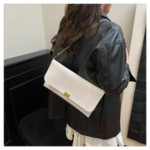 Détail du sac enveloppe en cuir blanc avec chaîne dorée et fermoir métallique chic