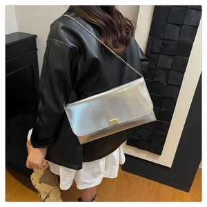 Détail d'un sac carré vintage avec chaîne dorée et boucle sur une veste en cuir