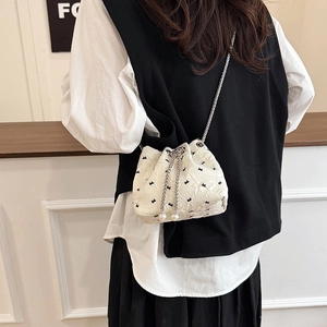 White bucket bag with black bow embroidery, pearl drawstrings and silver chain strap