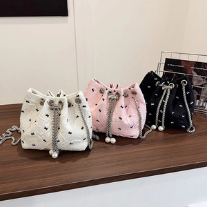 Chic drawstring bucket bag with bow embroidery, pearl details, and metal chain strap