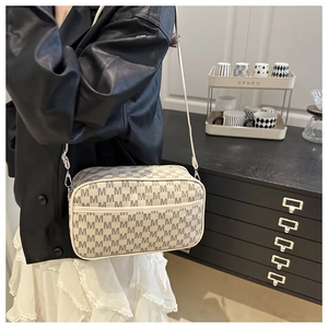 Dettaglio borsa a tracolla beige con motivo monogramma grigio e ganci metallici argentati