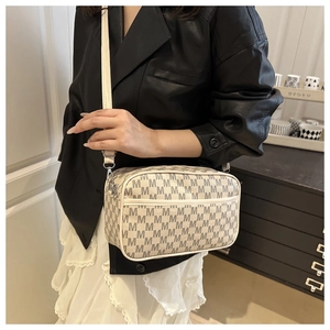 Detail of cream monogram crossbody bag with silver hardware on a female model