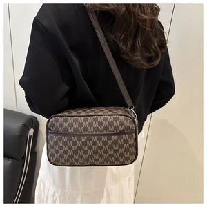 Détail du sac bandoulière marron foncé avec motif monogramme et bandoulière en cuir