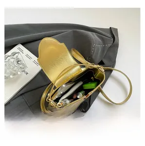 Vue intérieure du sac bandoulière doré montrant l'espace pour téléphone et maquillage