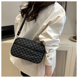 Crossbody bag detail with M-letter monogram pattern and adjustable nylon shoulder strap