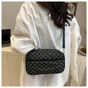 Detail of a vintage monogram crossbody bag on a model in a modern office setting