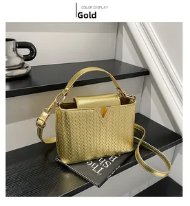 Detail shot of golden textured woven crossbody bag with elegant V-shaped metal buckle