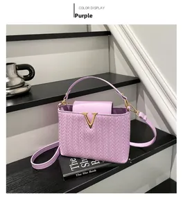 Detail of purple woven texture handbag with golden V-shaped buckle on a tiered background