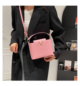 Détail du sac seau rose à texture tissée avec logo métallique doré en forme de V
