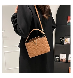 Gros plan du sac à bandoulière tressé marron avec boucle en métal V dorée