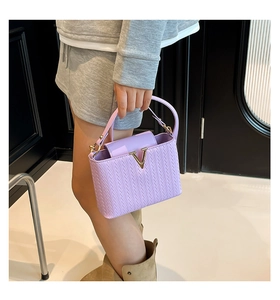 Gros plan d'un sac à main tissé violet clair avec fermoir métallique doré en forme de V