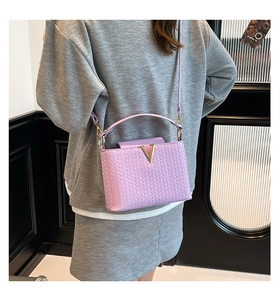 Detail view of purple woven texture on small square bag with gold V-shape buckle