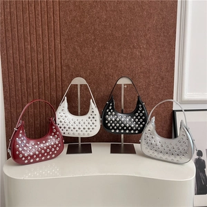 Eleganti borse hobo con borchie in rosso, bianco, nero e argento su stand minimalista