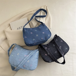 Three denim shoulder bags with colorful bow prints shown in a stylish 45-degree flat lay view