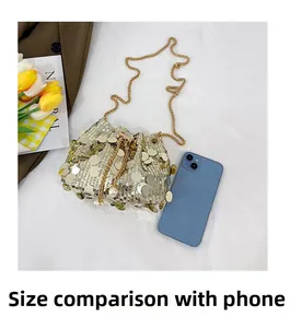 Detailed size comparison of golden sequin bucket bag with a mobile phone