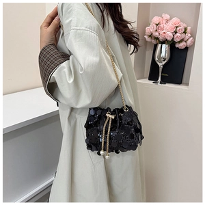 Detail of black sequin bucket bag with drawstring pearls and gold chain strap