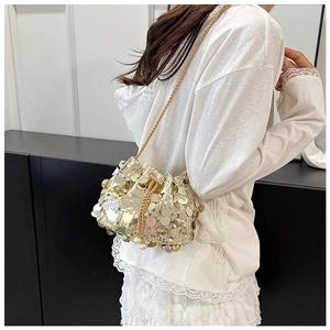 Detail of gold sequin bucket bag with chain strap and elegant pearl drawstring closure