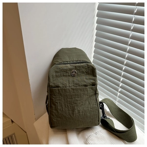 Détail du sac de poitrine en nylon vert armée avec logo en métal et bandoulière tissée