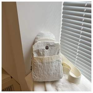 Détail du sac bandoulière en nylon blanc avec texture imperméable et logo en métal