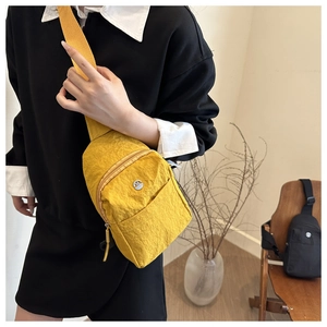 Détail du sac de poitrine en nylon jaune avec texture plissée et logo métallique