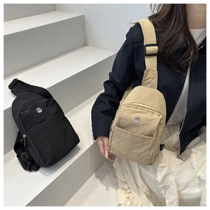 Detail of minimalist nylon chest bags in black and khaki with metallic M logo and multi-pockets