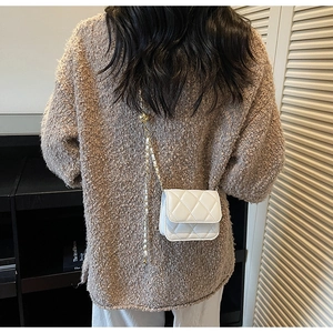 Détail du mini sac matelassé blanc avec bandoulière chaîne dorée et perle décorative
