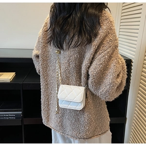 Mini sac bandoulière blanc matelassé avec chaîne dorée porté à l'épaule du mannequin