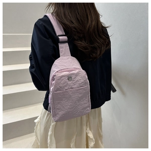 Gros plan d'un sac bandoulière en nylon lavande porté par un mannequin sur des escaliers