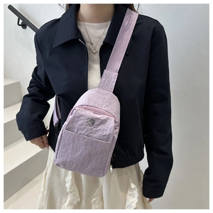 Close-up of lightweight lavender nylon crossbody bag with wide strap and metal logo detail
