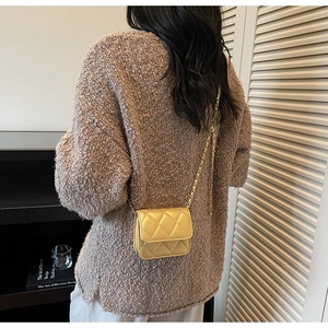 Gros plan d'un mini sac matelassé jaune avec chaîne dorée sur un mannequin féminin