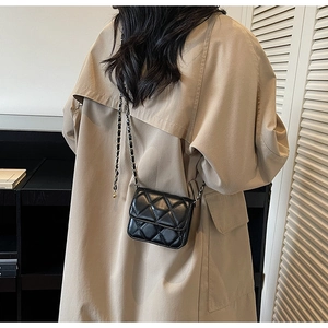 Vue détaillée du mini sac à rabat matelassé noir avec bandoulière chaîne sur un trench