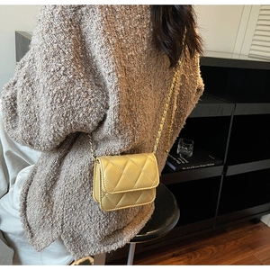 Détail du petit sac bandoulière jaune matelassé avec chaîne dorée sur l'épaule
