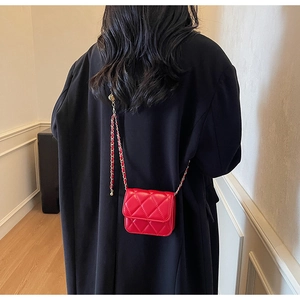 Sac bandoulière rouge matelassé porté par un mannequin sur fond minimaliste